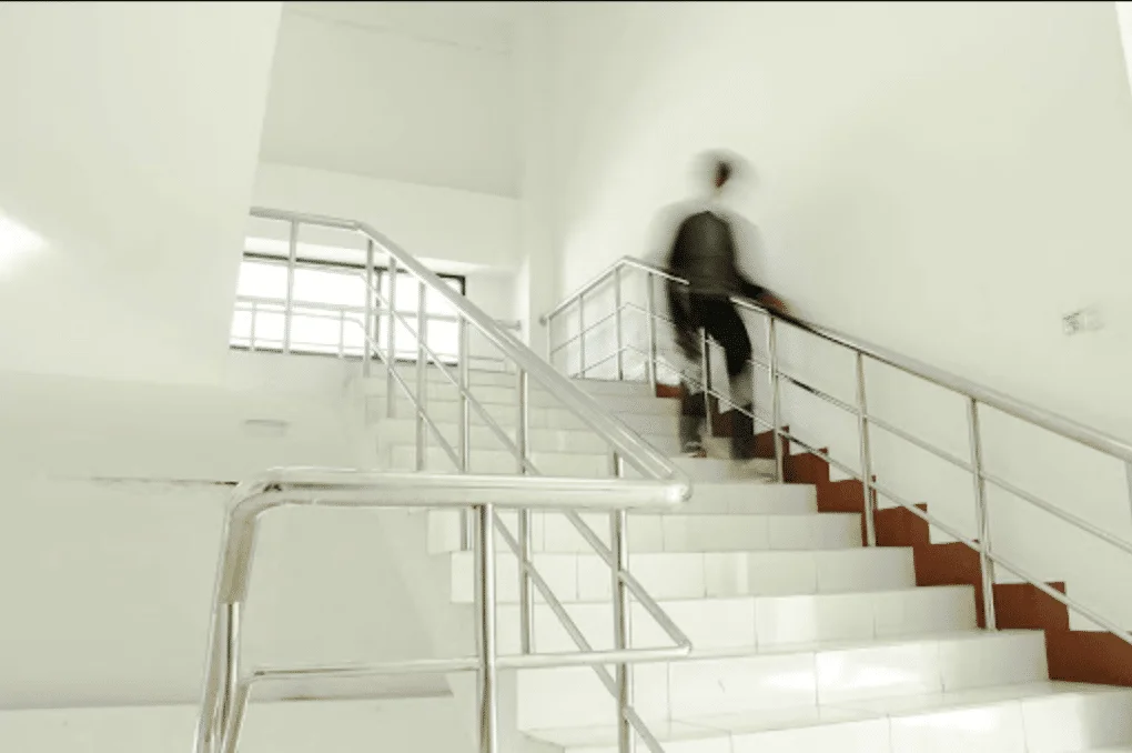 a-blurred-figure-climbs-a-white-staircase